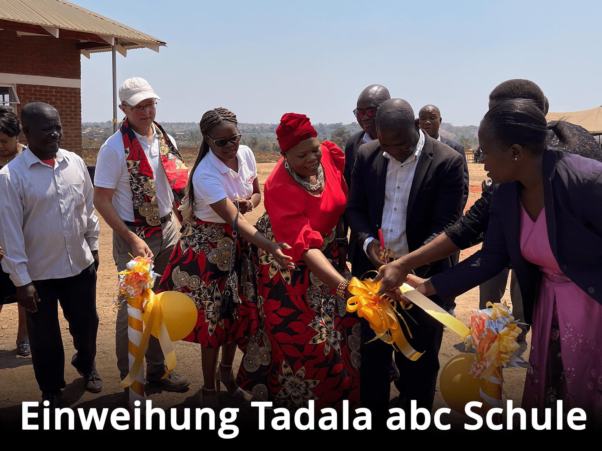 Feierliche Durchtrennung eines gelben Bandes bei der Einweihung und Eröffnung einer Schule im Rahmen des Schulbau-Spendenprojekts.