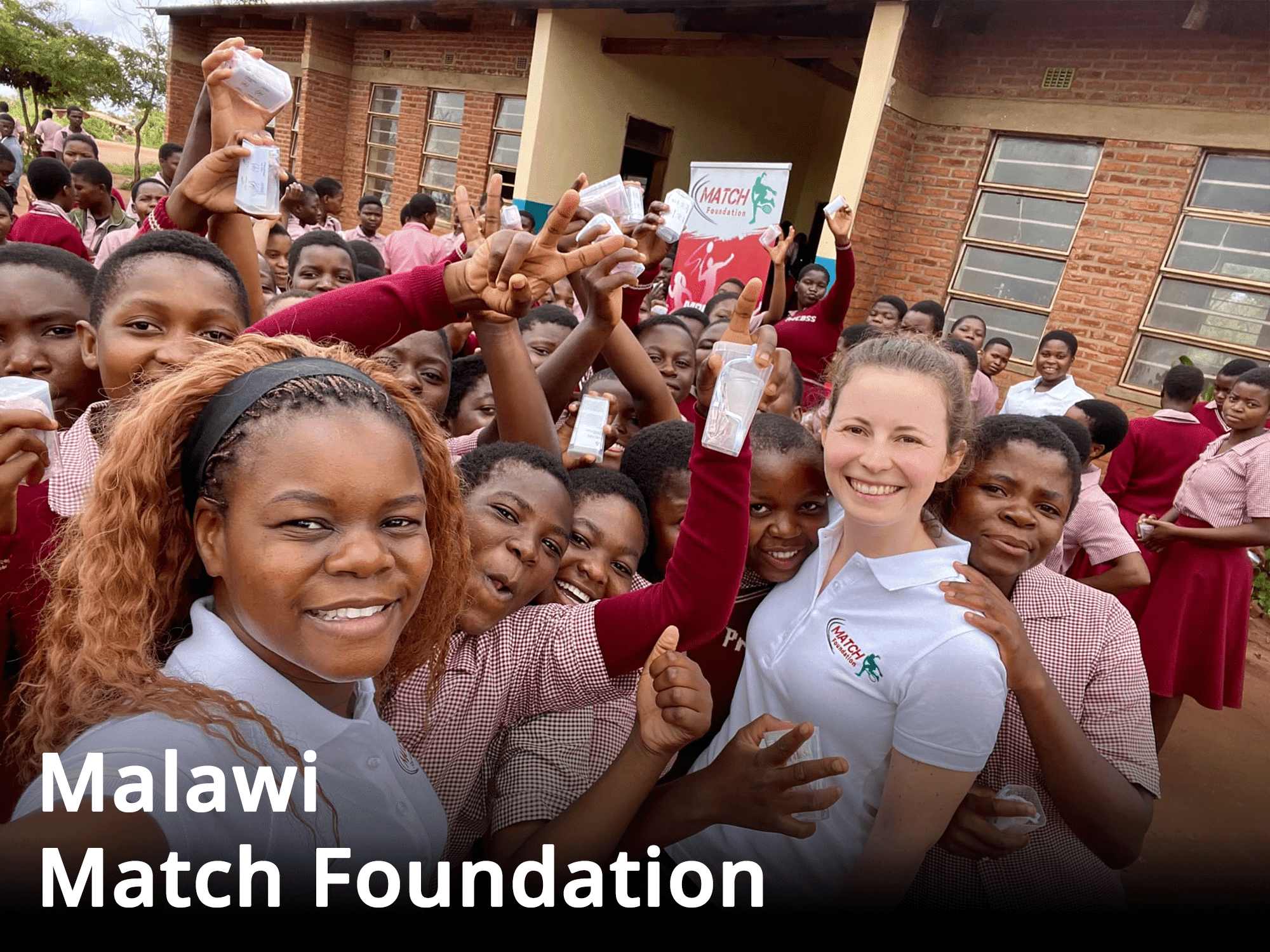 Eine Gruppe von Mädchen in rot karierten und weißen Hemden, die für das Malawi Match Foundation Spendenprojekt posiert.