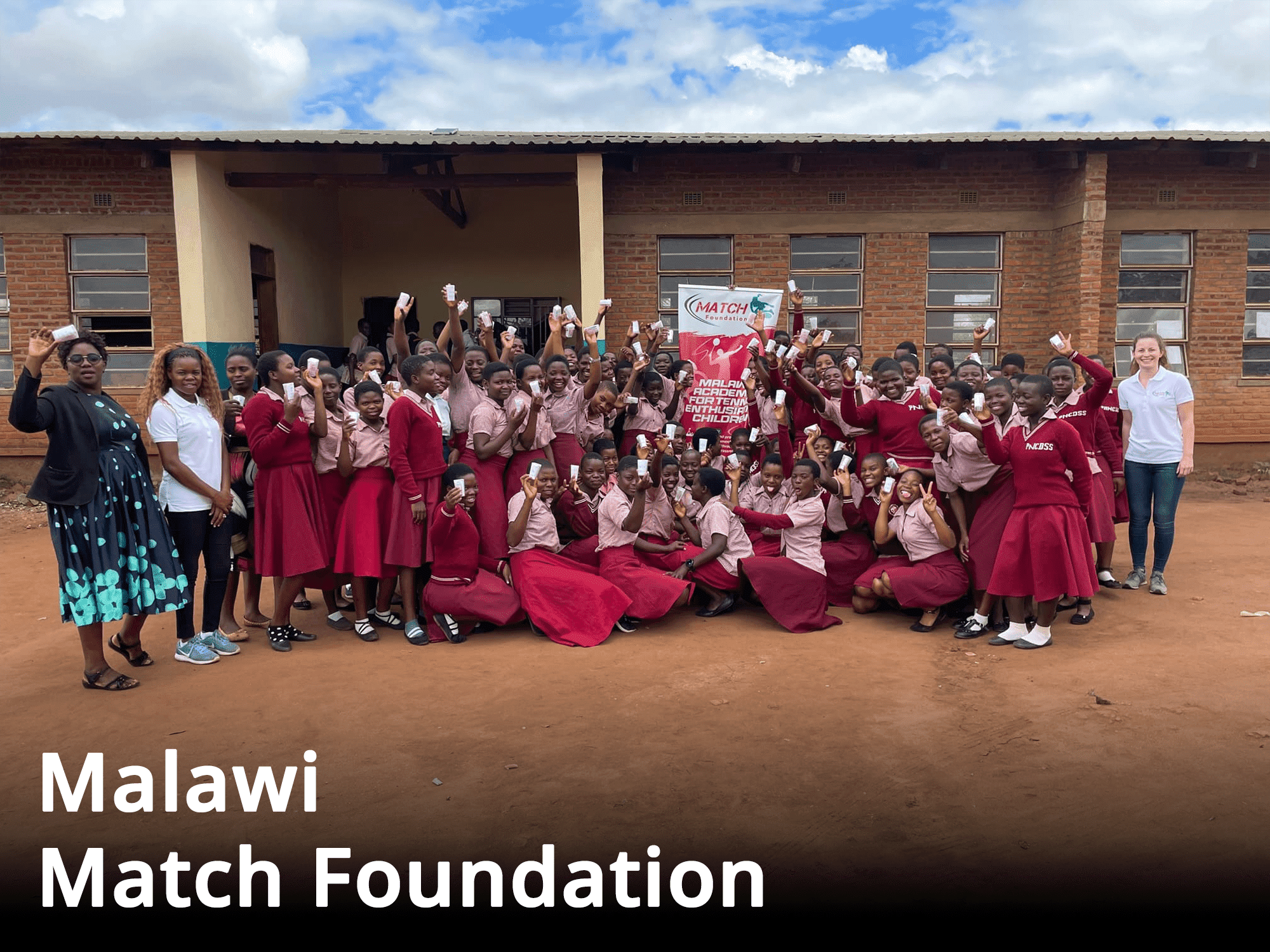 Eine Gruppe von Mädchen in roten Uniformen posiert für ein Foto im Rahmen des Malawi Match Foundation Spendenprojekts.