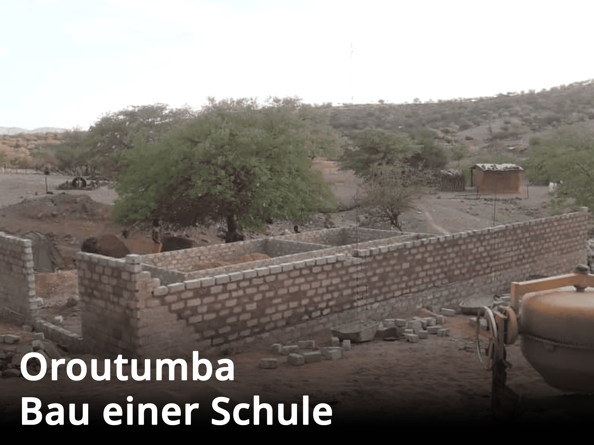 Ein im Bau befindliches Schulgebäude mit Ziegelmauer und Schotterstraße in Oroutumba.