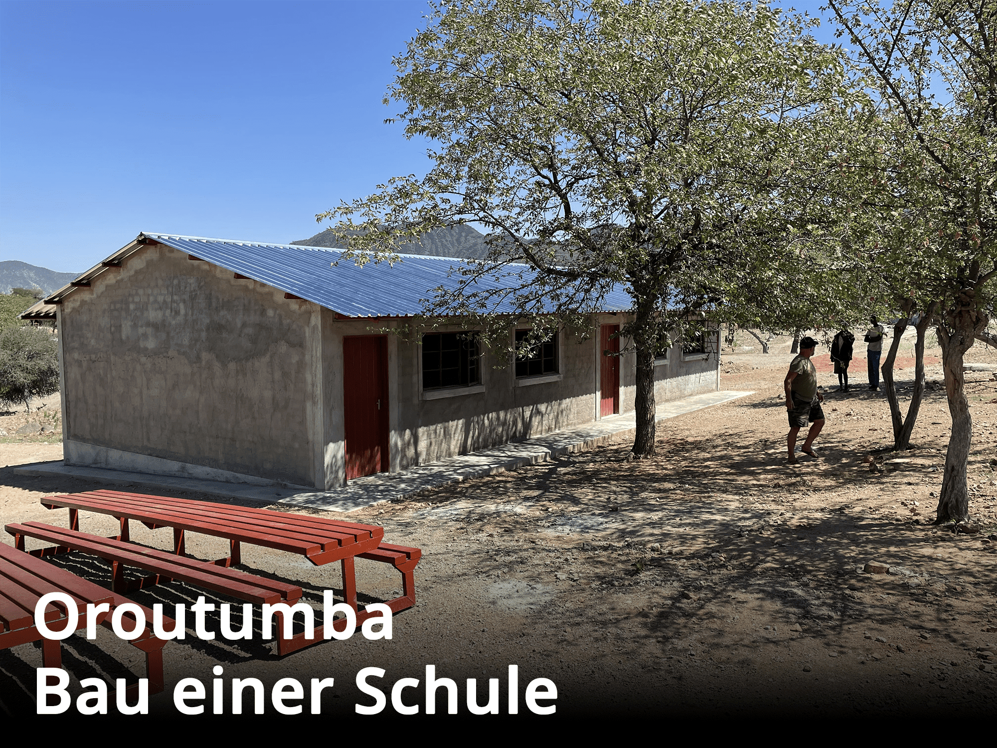 Das neue Schulgebäude in Oroutumba, umgeben von Bänken und Bäumen im Außenbereich.