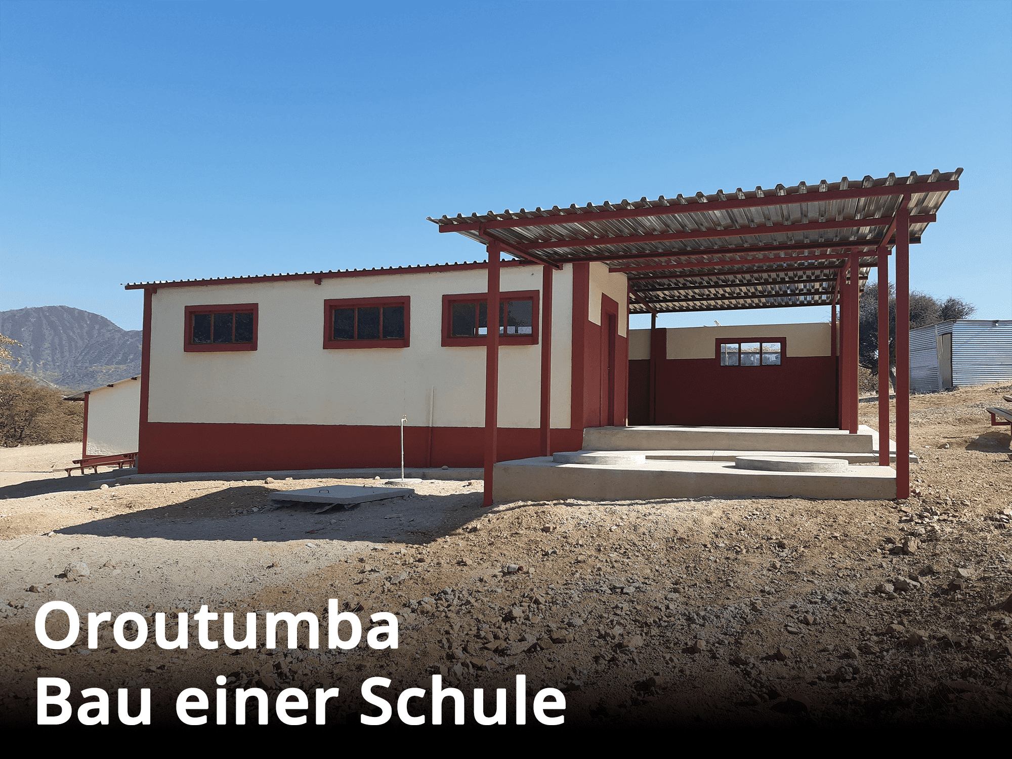 Die Hausfront des Schulgebäudes in Oroutumba mit einem schützenden Dach und einer Veranda.